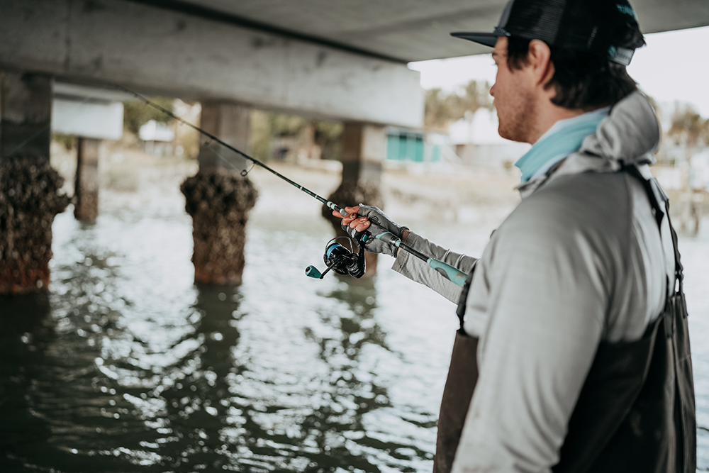 A Man fishing under a bridge 